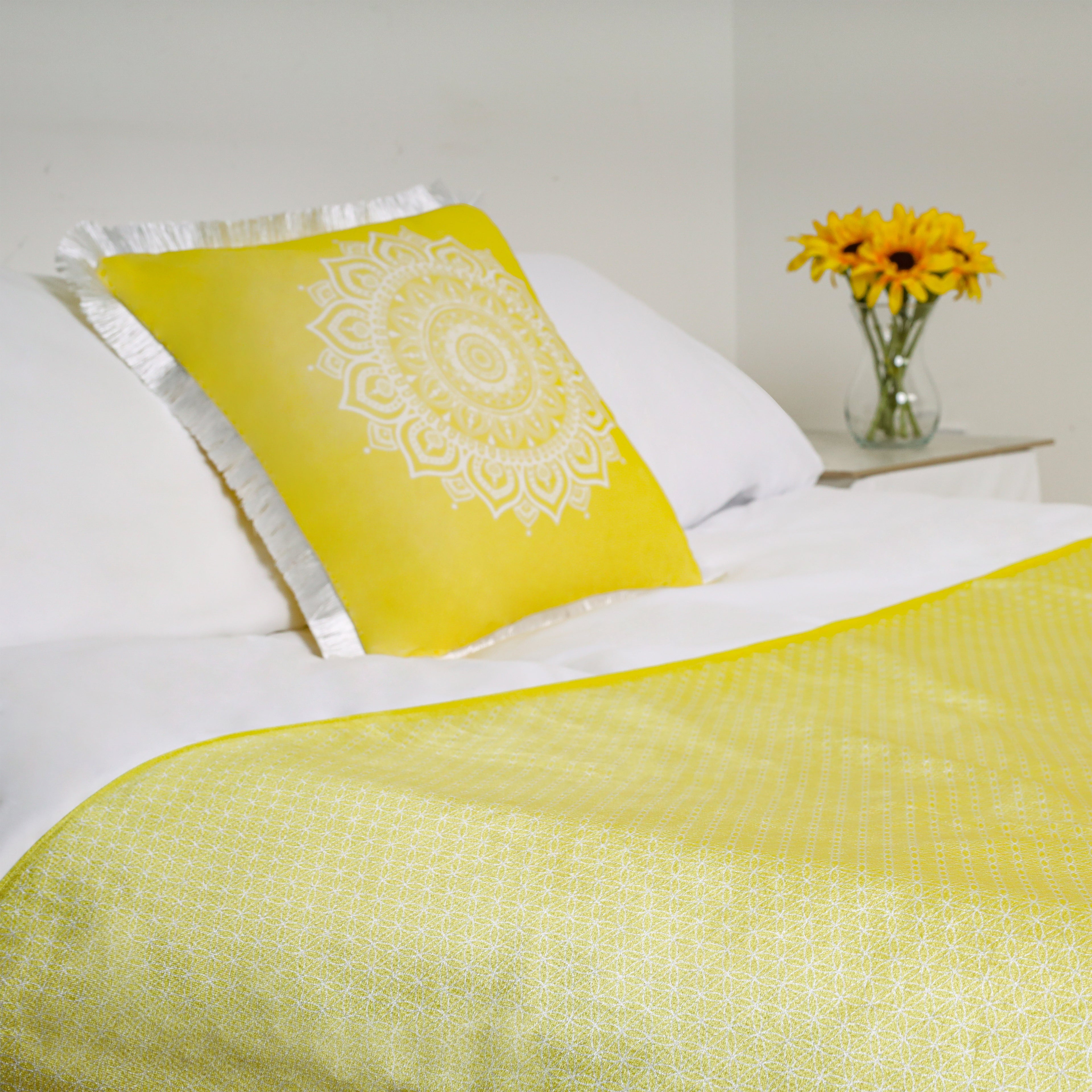 A yellow geometric bed runner on a white bed styled with a yellow geometric cushion