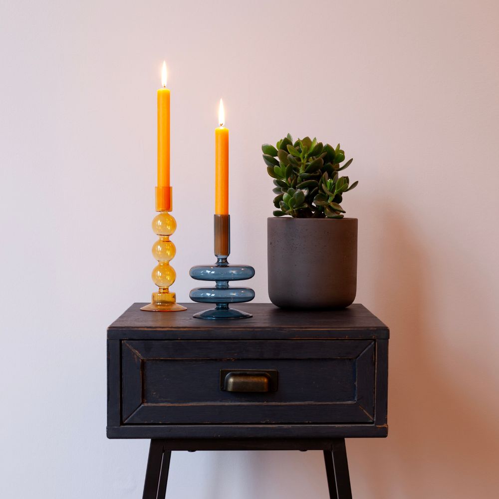 dopamine-decor-dinner-taper-candles-in-coloured-candle-holders-with-potted-plant-on-black-side-table-against-white-wall